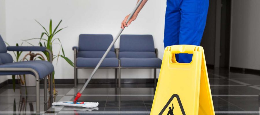 Close-up Of Man Cleaning The Floor With Yellow Wet Floor Sign